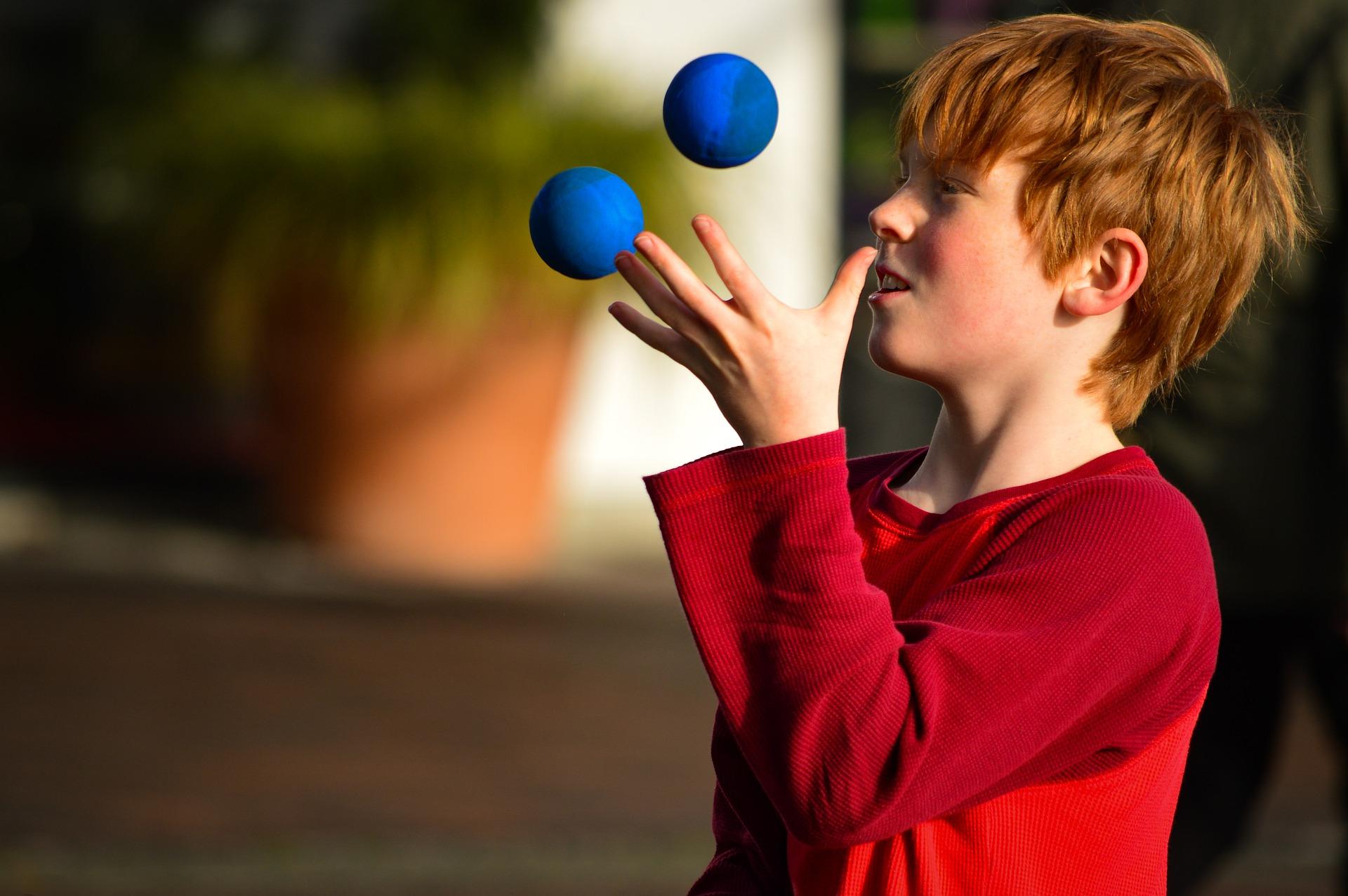 A red headed boy juggling balls